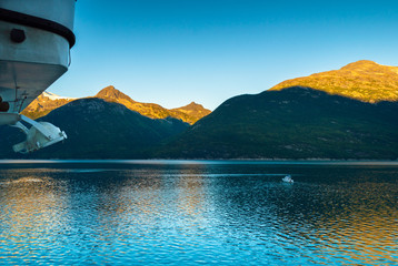 Taiya Inlet, mountains and small craft on calm early morning from deck of cruise ship, Skagway, Alaska.