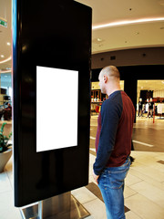 A man with Digital media blank black and white screen modern panel, signboard for advertisement design in a shopping center, gallery. Mockup, mock-up, mock up with blurred background, digital kiosk.