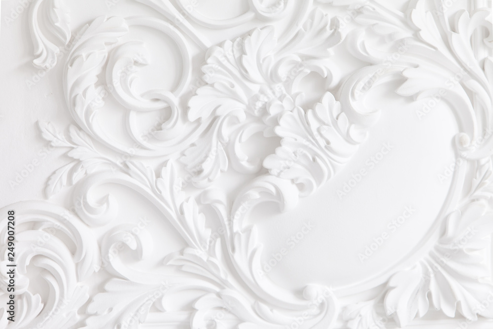 Beautiful ornate white decorative plaster mouldings in studio. The white wall is decorated with exquisite elements of plaster stucco - obrazy, fototapety, plakaty 