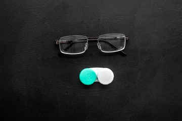 Wall Mural - Eyes care. Glasses with transparent lenses and contact lenses on black background top view space for text