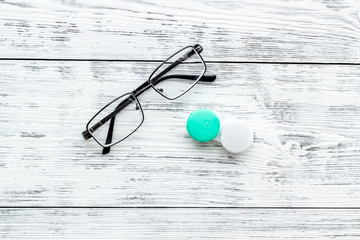 Wall Mural - Eyes care. Glasses with transparent lenses and contact lenses on white wooden background top view copy space