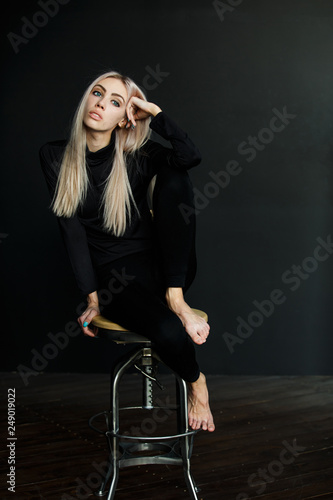Beautiful Blonde In A Black Suit On A Black Background Sitting On