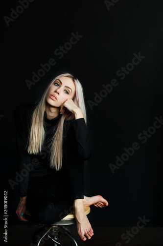 Beautiful Blonde In A Black Suit On A Black Background Sitting On