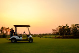 Golf cart car in fairway of golf course with fresh green grass field and cloud sky and tree  on sunset time