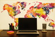 Colorful abstract world map on a desk with notebook, office accessories and glass of water 