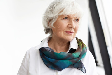 horizontal image of attractive fashionable retired female wearing white shirt and elegant silk scarf