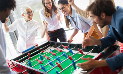 Multicultural business people celebrating win while playing table football