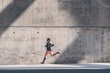 © KleverLevel - Muscular Male athlete sprinter running fast,exercising outdoors,jogging outside against gray concret background with copy space area for text message or ad content.Side view,full length