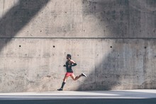 Muscular Male Athlete Sprinter Running Fast,exercising Outdoors,jogging Outside Against Gray Concret Background With Copy Space Area For Text Message Or Ad Content.Side View,full Length