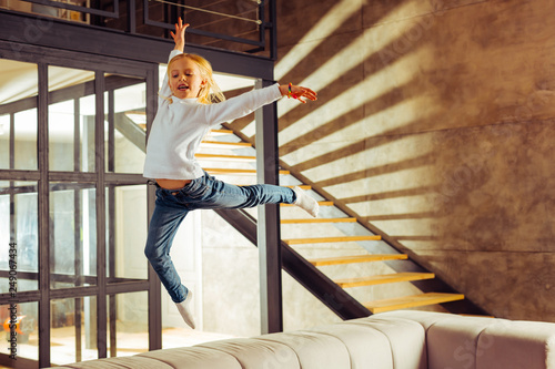 Fotografía Positive delighted little female jumping on sofa