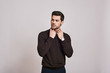 © Friends Stock - He cares about his style. Young dark-haired man wearing brown jumper standing over grey background