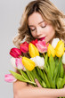 © LIGHTFIELD STUDIOS - young attractive spring woman with closed eyes holding bouquet of colorful tulips isolated on grey