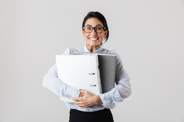 Wall Mural - Photo of successful female worker wearing eyeglasses holding paper folders in the office, isolated over white background
