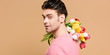 © LIGHTFIELD STUDIOS - cheerful man holding bouquet of flowers on shoulder isolated on beige