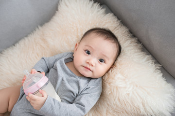 Asian baby infant eating milk from bottle, 9 months after birth