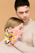 © LIGHTFIELD STUDIOS - tender man with alstroemeria flowers on hand touching face of beautiful girlfriend isolated on beige