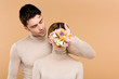 © LIGHTFIELD STUDIOS - handsome man with alstroemeria flowers on hand covering face of girlfriend isolated on beige
