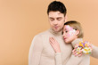 © LIGHTFIELD STUDIOS - tender woman with flowers on face hugging handsome man isolated on beige