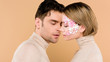 © LIGHTFIELD STUDIOS - handsome man looking at pretty girlfriend with closed eyes isolated on beige