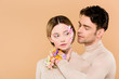 © LIGHTFIELD STUDIOS - tender man with alstroemeria flowers on hand touching face of beautiful girlfriend isolated on beige