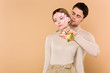 © LIGHTFIELD STUDIOS - handsome man with alstroemeria flowers on hand touching neck of beautiful girlfriend isolated on beige