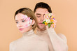 © LIGHTFIELD STUDIOS - handsome man with alstroemeria flowers on hand covering one eye near beautiful girlfriend isolated on beige