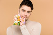 © LIGHTFIELD STUDIOS - man with alstroemeria flowers on hand touching lips isolated on beige