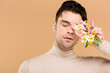 © LIGHTFIELD STUDIOS - tender man with alstroemeria flowers on hand covering one eye isolated on beige