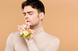 © LIGHTFIELD STUDIOS - man with alstroemeria flowers on hand showing hush sign isolated on beige