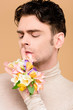 © LIGHTFIELD STUDIOS - handsome man with alstroemeria flowers on hand showing hush sign isolated on beige