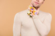 © LIGHTFIELD STUDIOS - cropped view of man with alstroemeria flowers on hand touching neck isolated on beige