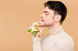 © LIGHTFIELD STUDIOS - profile of handsome man with alstroemeria flowers on hand showing hush sign isolated on beige
