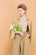 © LIGHTFIELD STUDIOS - attractive woman in beret holding bouquet isolated on beige