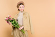 © LIGHTFIELD STUDIOS - trendy woman holding bouquet with flowers isolated on beige