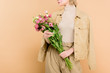 © LIGHTFIELD STUDIOS - cropped view stylish woman with flowers on face holding bouquet isolated on beige