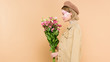© LIGHTFIELD STUDIOS - side view of stylish woman with flowers on face holding bouquet isolated on beige