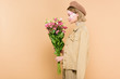 © LIGHTFIELD STUDIOS - profile of stylish woman with flowers on face holding bouquet isolated on beige