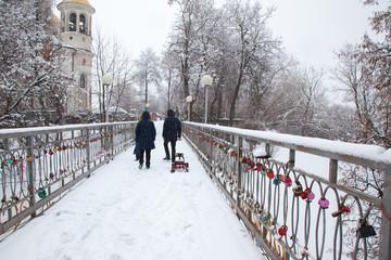 Locks with red hearts on the railing of the bridge.The backs of a family with a child.