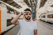 © KleverLevel - Happy Traveler male discover a big europe city, travel and active lifestyle concept.Bearded hispanic Tourist Man in white tshirt waiting his train on railway station