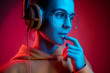 © master1305 - Fashion pretty woman with headphones listening to music over red neon background at studio.