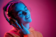 © master1305 - Fashion pretty woman with headphones listening to music over red neon background at studio.