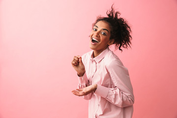 Poster - Beautiful young african woman posing isolated over pink wall background imagine that she drinking tea.