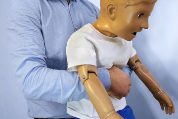 Abdominal thrusts (the Heimlich maneuver or Heimlich manoeuvre) on a simulation mannequin child dummy during medical training Basic Life Support