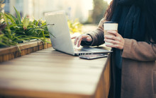 Young Cute Woman With Laptop And Coffee Outdoor On Wooden Urban Terrace