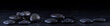 Panoramic image of zen stones with water drops on a black background