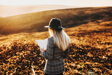 Beautiful blonde european woman reading outside against sunset in front of a amazing view.