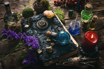 Spell book, magic potions and other various witchcraft accessories on the wizard table background.