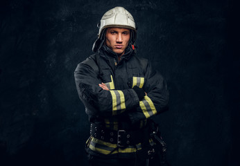 Wall Mural - Manly firefighter in helmet looks into camera in studio on black background