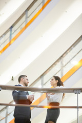 Wall Mural - Two young colleagues with drinks discussing some details of new project or deal inside trade center