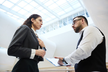 Wall Mural - Strict boss pointing at document while asking his secretary to explain mistake in contract